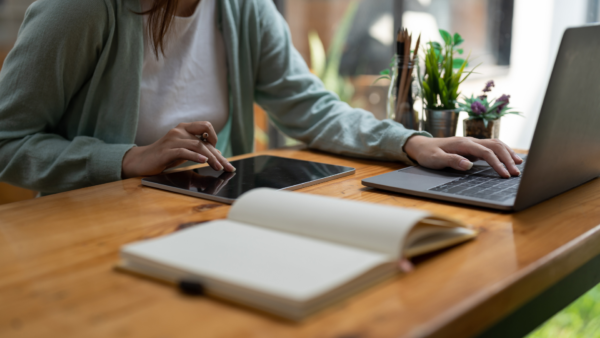 Person studying online with a laptop and a book on the table